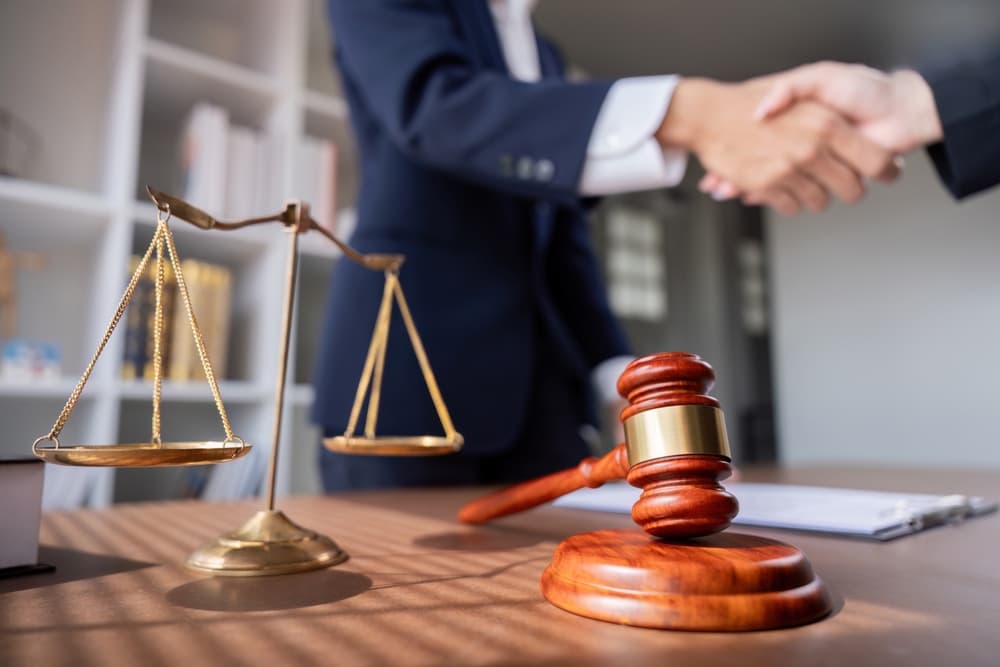 Professional Lawyer Handshake in Business Meeting with Scales of Justice and Gavel on Desk.